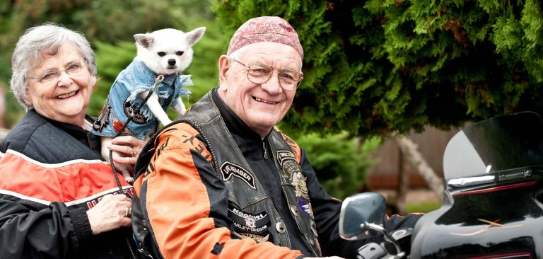independent living showing a senior couple and their little dog on a motorcycle